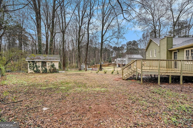 view of yard with an outdoor structure, fence, and a wooden deck