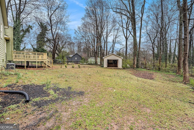 view of yard with a deck, an outdoor structure, fence, and a shed