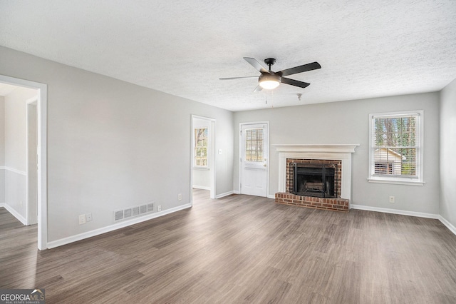 unfurnished living room featuring visible vents, baseboards, ceiling fan, a fireplace, and wood finished floors