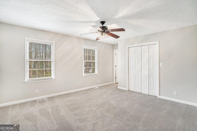 unfurnished bedroom featuring visible vents, baseboards, carpet, a closet, and a textured ceiling