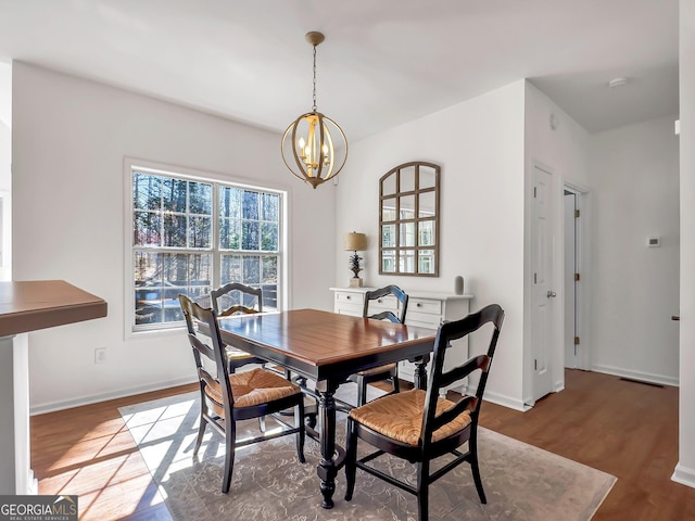 dining room featuring wood finished floors, baseboards, and a chandelier