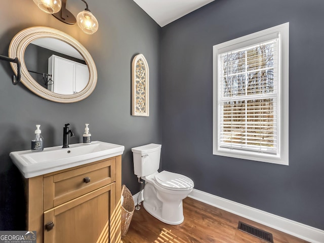 bathroom with visible vents, baseboards, toilet, wood finished floors, and vanity