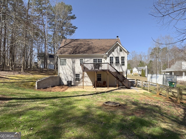 rear view of house featuring a wooden deck, an outdoor fire pit, a chimney, stairs, and a lawn