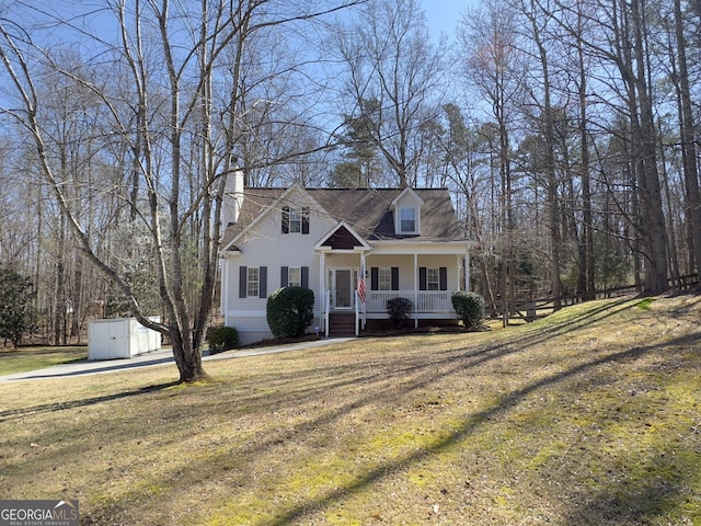 cape cod house featuring an outbuilding, covered porch, and a front yard