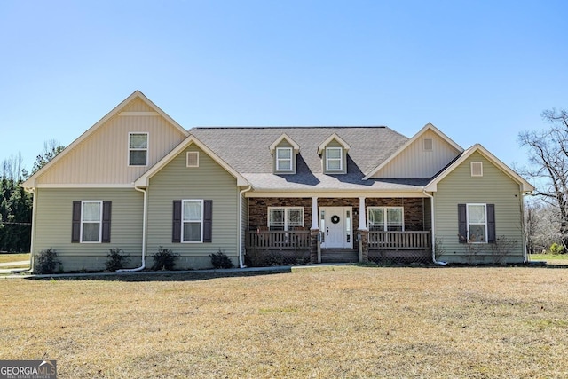 view of front facade featuring a front yard, a porch, and a shingled roof