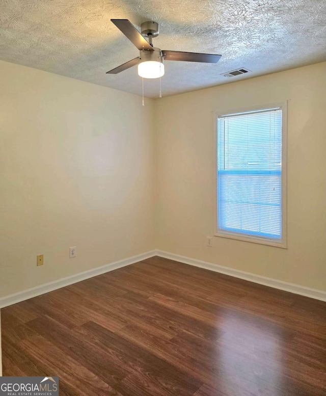 spare room with a textured ceiling, baseboards, and wood finished floors