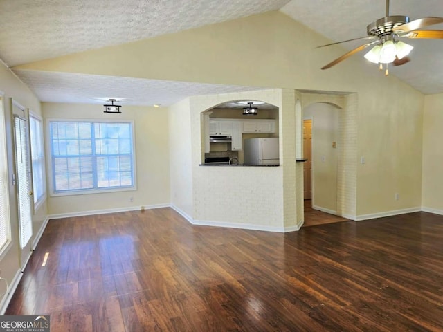 unfurnished living room featuring arched walkways, dark wood-style flooring, a textured ceiling, and vaulted ceiling