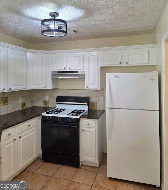 kitchen featuring under cabinet range hood, white cabinets, freestanding refrigerator, and gas range oven