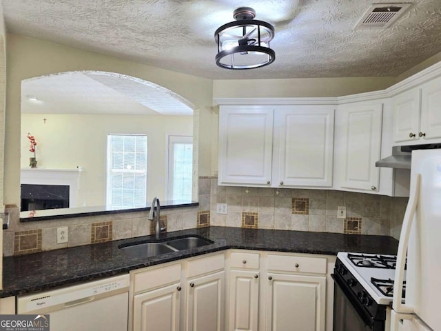 kitchen featuring visible vents, arched walkways, white cabinets, white appliances, and a sink