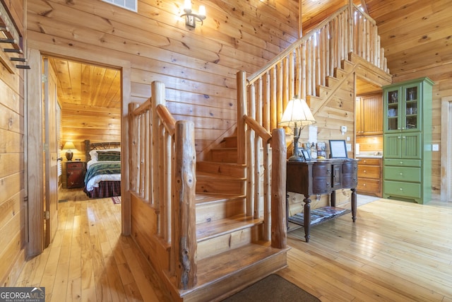 stairs featuring vaulted ceiling, wooden walls, wood ceiling, and hardwood / wood-style floors