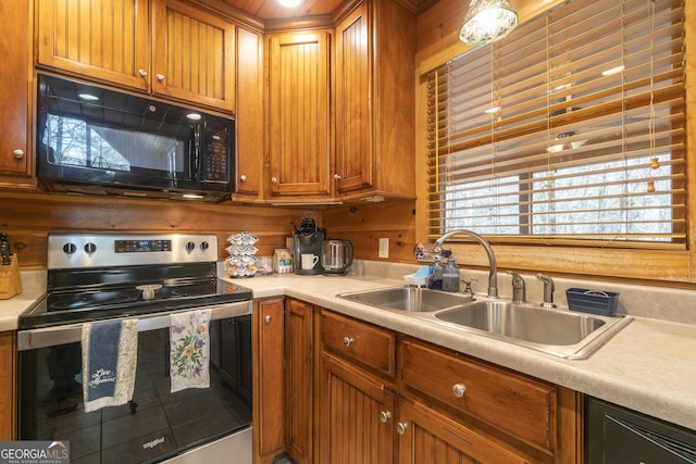 kitchen with black microwave, stainless steel electric stove, light countertops, brown cabinetry, and a sink