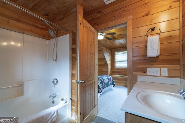 ensuite bathroom with connected bathroom, wood walls, wood ceiling, shower / bathing tub combination, and vanity