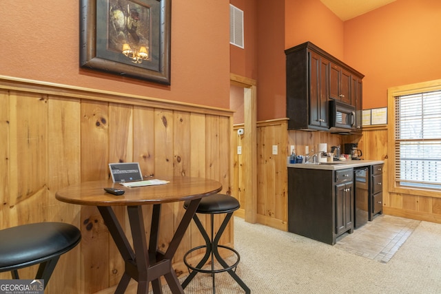 kitchen with black appliances, visible vents, wood walls, and wainscoting