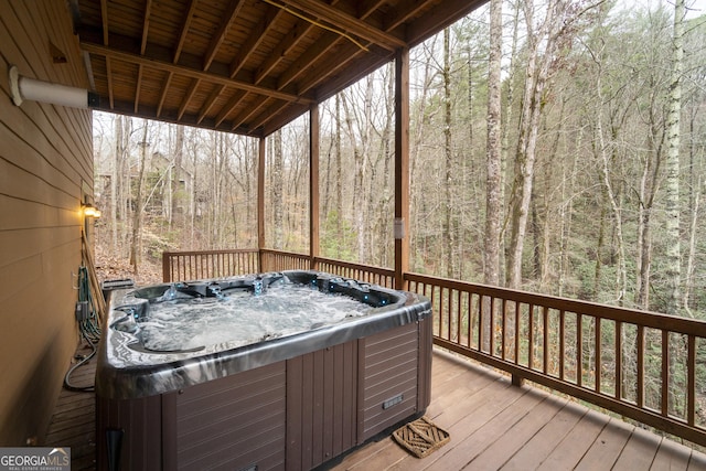 wooden terrace with a view of trees and a hot tub