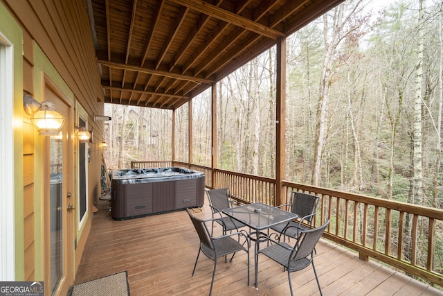 wooden deck with central air condition unit, outdoor dining area, a forest view, and a hot tub