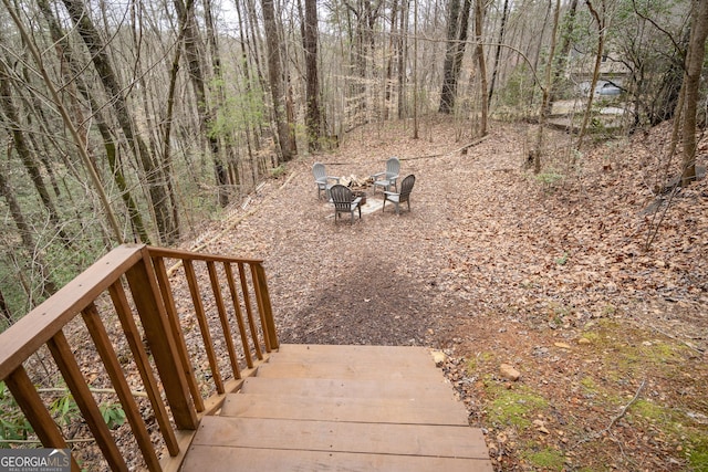 view of yard with a view of trees and an outdoor fire pit