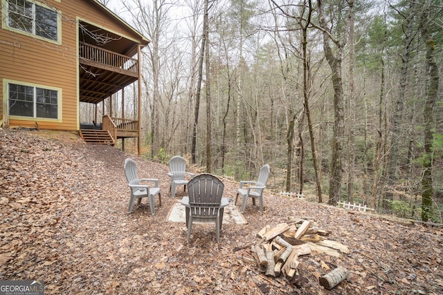 view of yard with a forest view, a balcony, and an outdoor fire pit