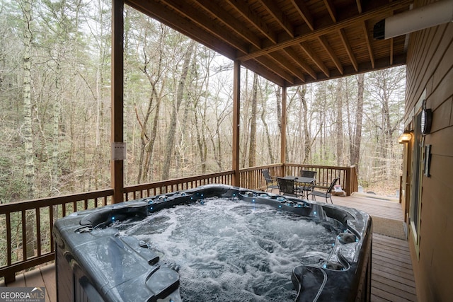 wooden deck with a hot tub and a forest view