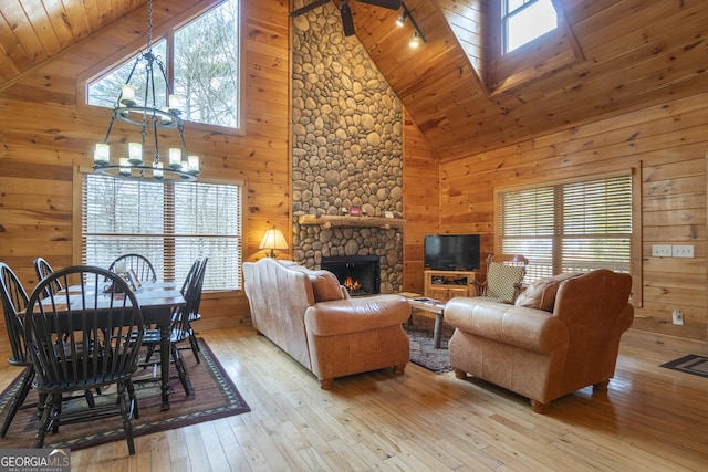 living room featuring a stone fireplace, hardwood / wood-style flooring, wooden walls, and a wealth of natural light