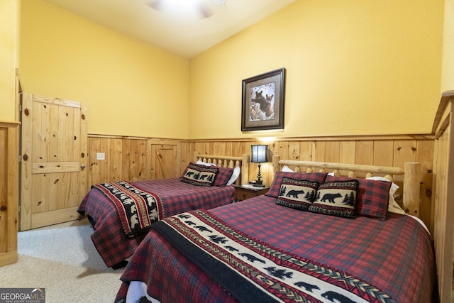 bedroom with carpet flooring, wainscoting, and wood walls