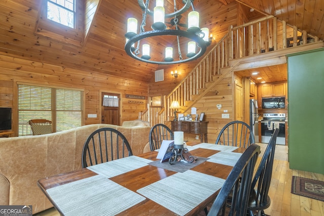 dining room featuring wooden walls, visible vents, a chandelier, wood ceiling, and light wood-style flooring