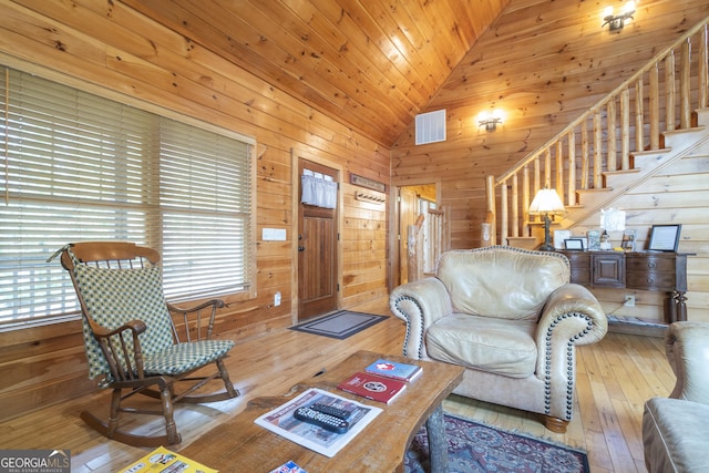 living room with stairway, wood walls, lofted ceiling, and hardwood / wood-style flooring