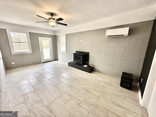 unfurnished living room with a wall unit AC, a ceiling fan, brick wall, a wood stove, and crown molding