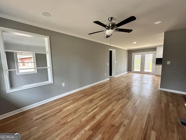 spare room with wood finished floors, a ceiling fan, baseboards, and ornamental molding