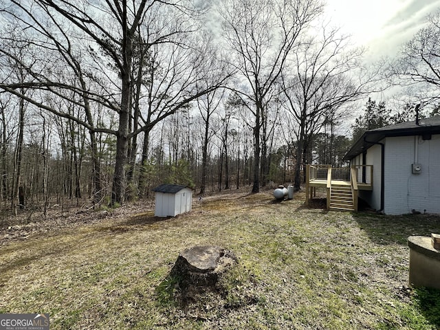 view of yard featuring a storage unit, a deck, an outdoor structure, and stairway