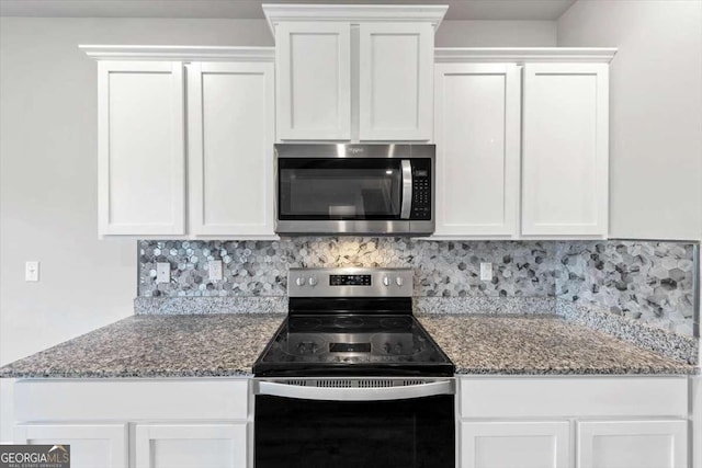 kitchen with stainless steel microwave, backsplash, white cabinets, and black range with electric stovetop