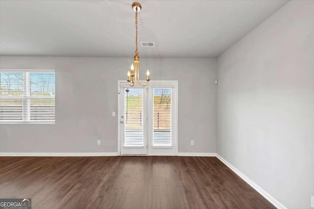 unfurnished dining area with visible vents, dark wood-style floors, baseboards, and a chandelier