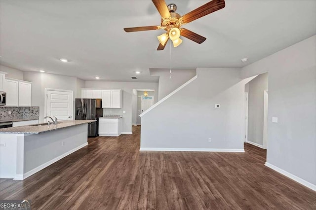 kitchen featuring dark wood-type flooring, a sink, stainless steel microwave, backsplash, and black refrigerator with ice dispenser