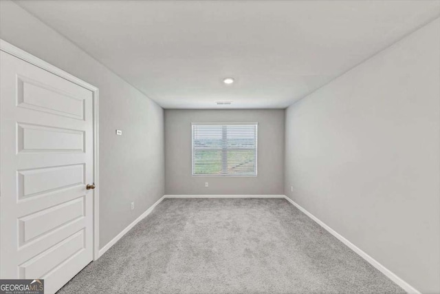 carpeted spare room featuring visible vents and baseboards