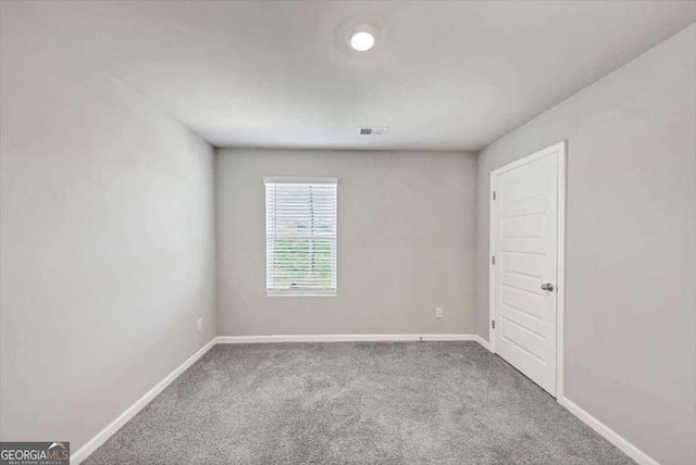 empty room with baseboards, visible vents, and carpet floors