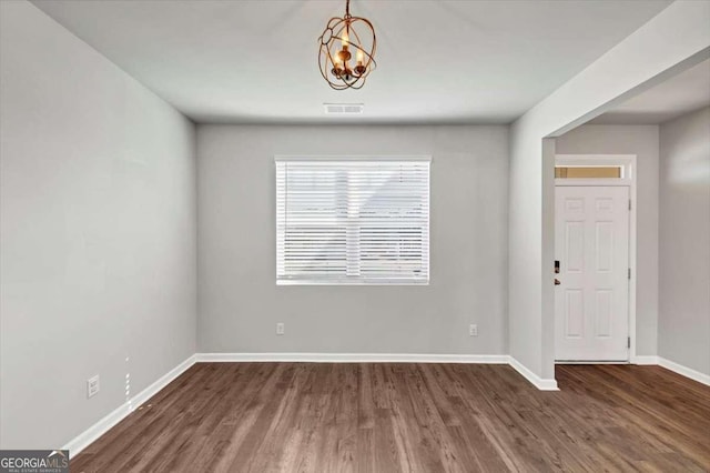 empty room with visible vents, baseboards, wood finished floors, and a chandelier