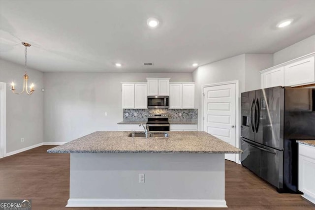 kitchen with dark wood-style floors, a sink, stainless steel appliances, white cabinetry, and tasteful backsplash