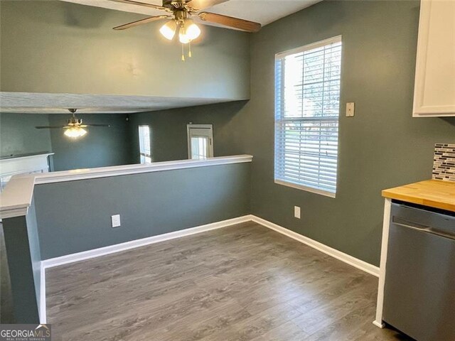 kitchen featuring a ceiling fan, stainless steel dishwasher, wood finished floors, white cabinetry, and baseboards