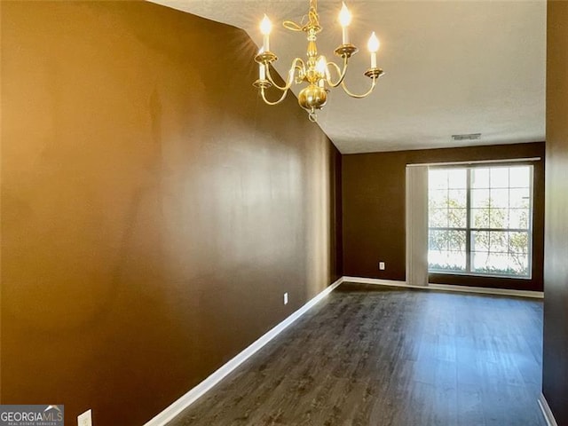 unfurnished dining area featuring a chandelier, visible vents, dark wood-type flooring, and baseboards