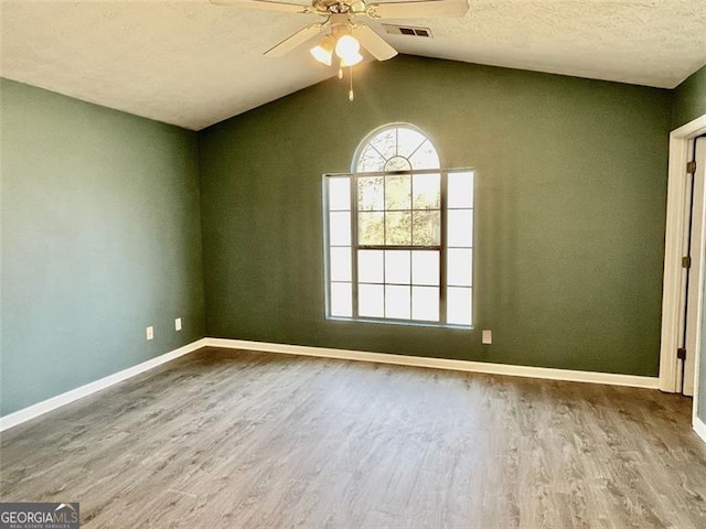 unfurnished room featuring baseboards, lofted ceiling, and wood finished floors