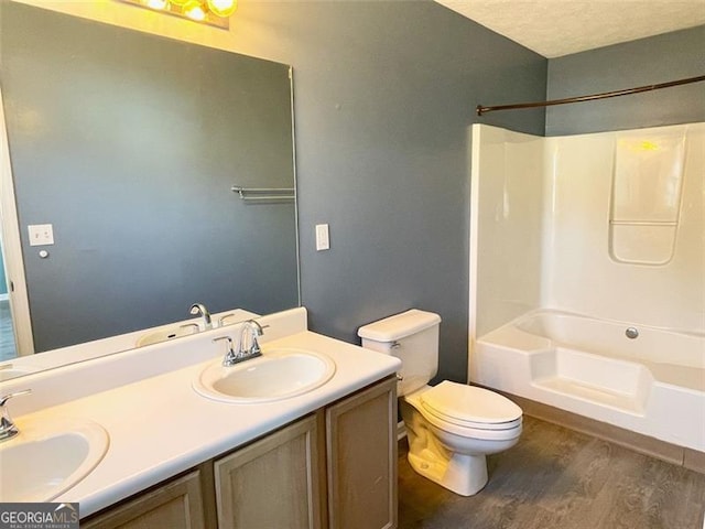 bathroom with wood finished floors, toilet,  shower combination, and a sink