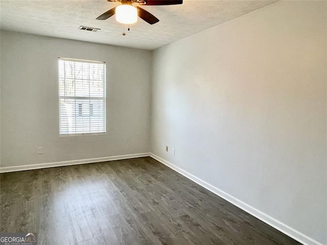 spare room featuring visible vents, dark wood-type flooring, a textured ceiling, baseboards, and ceiling fan