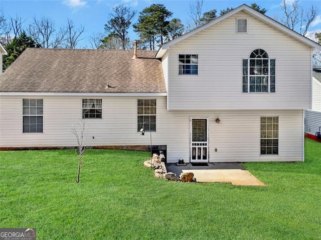 back of house featuring a patio, a lawn, and roof with shingles