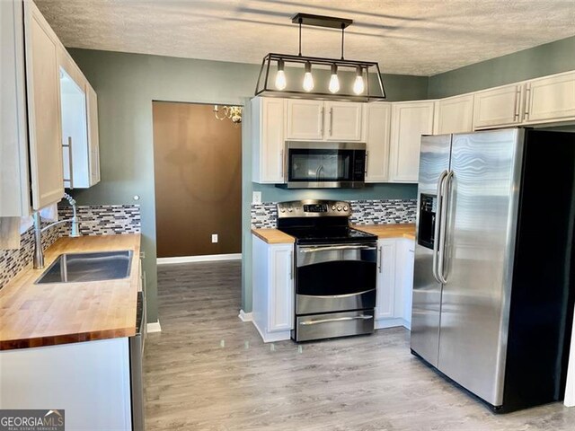 kitchen featuring a sink, stainless steel appliances, backsplash, and butcher block counters