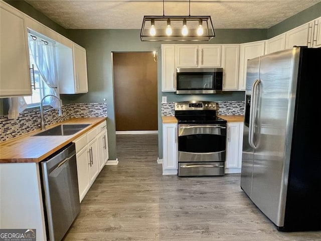 kitchen featuring backsplash, wooden counters, light wood-style floors, stainless steel appliances, and a sink