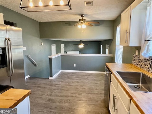 kitchen with stainless steel appliances, dark wood-type flooring, visible vents, and wood counters