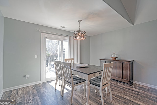 dining space with dark wood finished floors, visible vents, an inviting chandelier, and baseboards