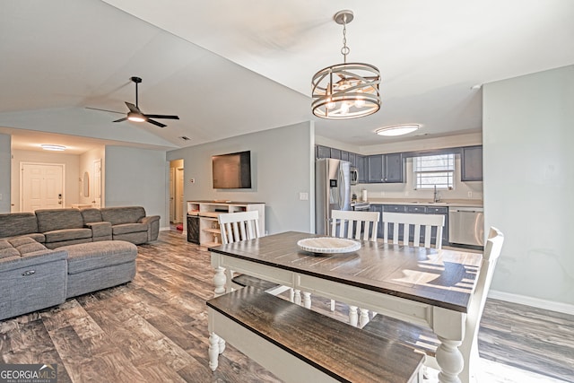 dining area with ceiling fan with notable chandelier, baseboards, lofted ceiling, and wood finished floors