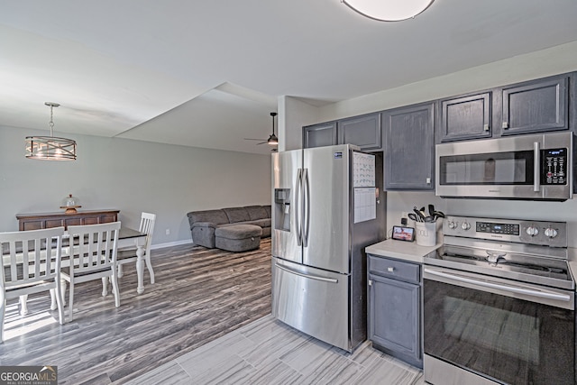 kitchen with a ceiling fan, decorative light fixtures, open floor plan, appliances with stainless steel finishes, and light countertops