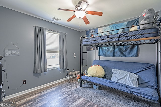 bedroom with ceiling fan, visible vents, baseboards, and wood finished floors