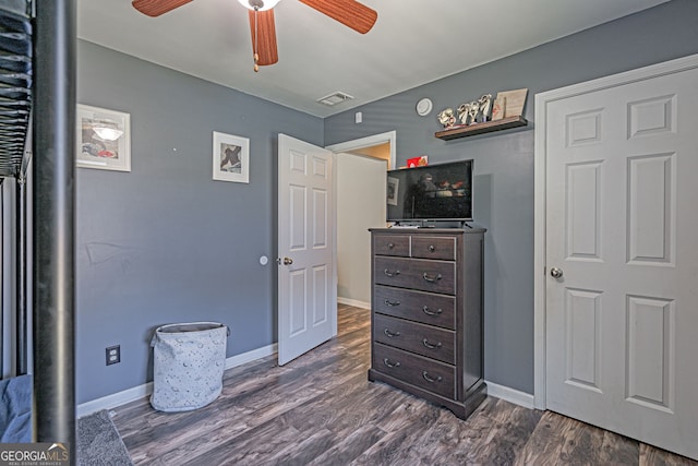 bedroom featuring a ceiling fan, visible vents, baseboards, and dark wood-style flooring